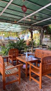 a patio with wooden tables and chairs and a green roof at topp stay hostel in Pai