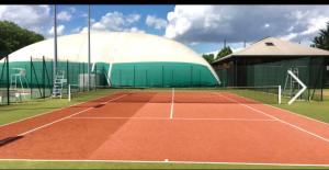 a tennis court with a large building and a tennis net at MaisonTevy - Appart 2 Chambres-4lits-Terrasse-Jardin & Studio-Confort-Climatisation- Idéale-Pro-Tourisme in Pontault-Combault