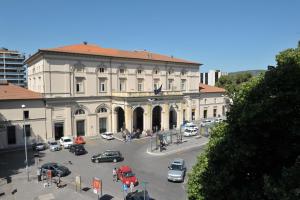 un gran edificio blanco con coches aparcados en un aparcamiento en Hotel Astor, en Perugia