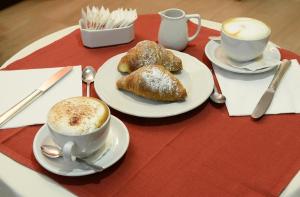 una mesa con dos tazas de café y pasteles. en Hotel Astor, en Perugia