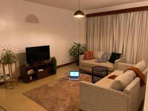 a living room with a couch and a laptop on a table at The Hillpoint Nest in Nairobi