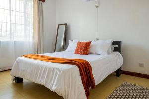 a bed with an orange blanket on it in a room at The Hillpoint Nest in Nairobi