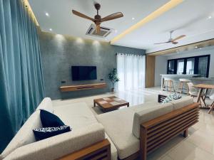 Una sala de estar con un sofá y un televisor de pantalla plana. en The Groove House Private Pool & BBQ by Linese Homestay, en Kuah