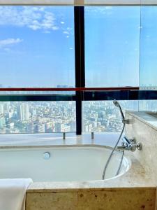 a bath tub in a bathroom with a large window at Swissotel Foshan, Guangdong in Foshan
