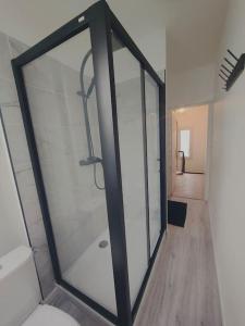 a glass shower door in a room with a hallway at Maison 8 couchages in Le Mans