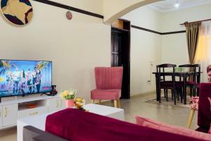 a living room with a couch and a tv at Cozy Apartment within Acacia mall area limits, Unlimited WIFI, Netflix, Free Parking in Kampala