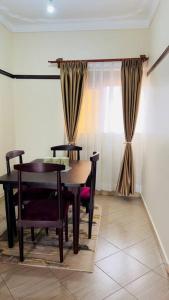 a dining room with a table and chairs and a window at Cozy Apartment within Acacia mall area limits, Unlimited WIFI, Netflix, Free Parking in Kampala