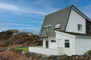 une maison blanche avec un toit noir sur une plage dans l'établissement Wellington Court-3 Bed-Pet friendly-Beachfront, à Trearddur