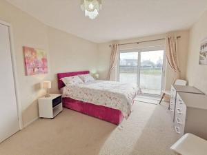 - une chambre avec un lit rose et une fenêtre dans l'établissement Wellington Court-3 Bed-Pet friendly-Beachfront, à Trearddur