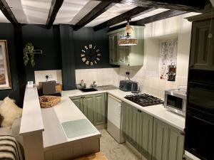 una cocina con armarios verdes y encimeras blancas en Granny Vera's @ Marigold Cottage en Bedale