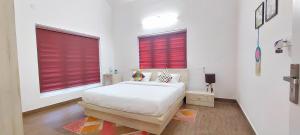 a white bedroom with red blinds on two windows at ROBUSTA FOREST Home stay in Sultan Bathery
