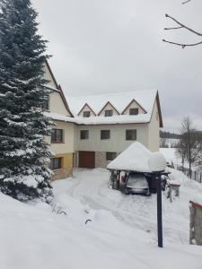 una casa coperta da neve con un'auto parcheggiata nel vialetto di Pokoje u Jasia i Małgosi a Skawa