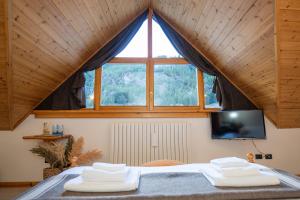 a bedroom with a large window and a bed with two towels at Fior di Roccia - Valmalenco - Hotel & Mountain Restaurant in Lanzada
