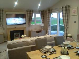 a living room with a couch and a table with wine glasses at Turnberry lodge in Girvan