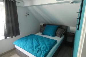 Cama en habitación pequeña con almohadas azules en Holiday, en Schwandorf