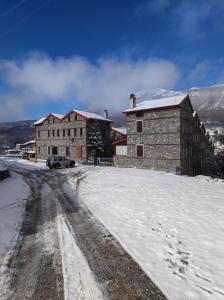un bâtiment dans la neige avec une voiture garée à côté dans l'établissement Cozy Mountain Villa in P. Agios Athanasios, à Palaios Agios Athanasios