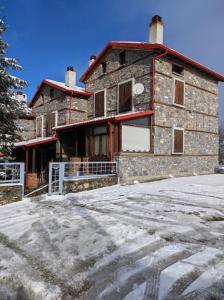 a building with snow on the ground in front of it at Cozy Mountain Villa in P. Agios Athanasios in Palaios Agios Athanasios