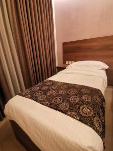 um quarto com uma cama com um cobertor castanho e branco em Dara apartment hotel em Umm Uthainah