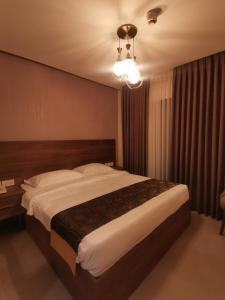 Un dormitorio con una cama grande y una lámpara de araña. en Dara apartment hotel en Umm Uthainah