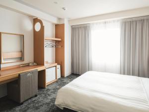 Habitación de hotel con cama, escritorio y TV. en Vessel Hotel Ishigakijima en Isla Ishigaki