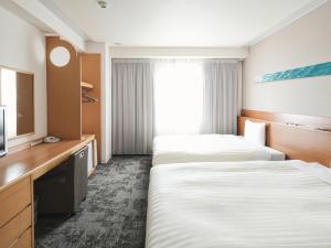a hotel room with two beds and a television at Vessel Hotel Ishigakijima in Ishigaki Island