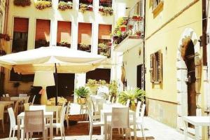 un restaurant avec des tables et des chaises blanches ainsi qu'un parasol dans l'établissement Art Of Living - Esclusivo 130 MQ, à Isernia