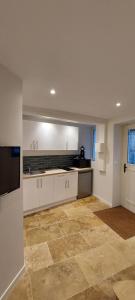 une cuisine avec des armoires blanches et un sol carrelé dans l'établissement APPARTEMENT LES MOUETTES, à Saint-Valery-en-Caux