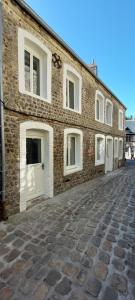 - un bâtiment en briques avec des portes blanches sur une rue pavée dans l'établissement APPARTEMENT LES MOUETTES, à Saint-Valery-en-Caux