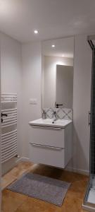 une salle de bain blanche avec un lavabo et un miroir dans l'établissement APPARTEMENT LES MOUETTES, à Saint-Valery-en-Caux 11 autres photos