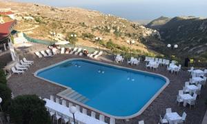 a large swimming pool with white chairs and a mountain at Santangelo Hotel in Monte SantʼAngelo