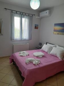 sypialnia z różowym łóżkiem i ręcznikami w obiekcie SummerAndros Windmill w mieście Andros