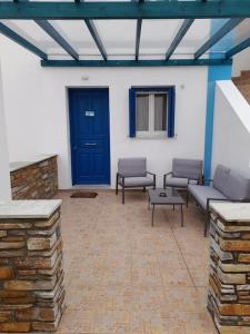 eine Terrasse mit einer blauen Tür, Stühlen und einem Tisch in der Unterkunft SummerAndros Windmill in Ándros