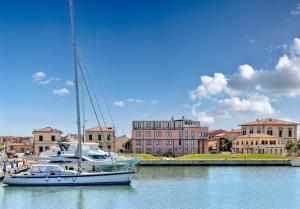 a sailboat is docked in a harbor with buildings at L'incanto Di Boccadarno in Marina di Pisa