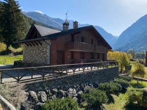a large wooden house with a stone wall in front at Mansarda Santa Chiara - AffittiPontediLegno in Temù