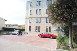two cars parked in a parking lot in front of a building at L'incanto Di Boccadarno in Marina di Pisa