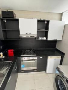 Shiny appartment in Prestigia في الرباط: مطبخ صغير مع موقد ودواليب بيضاء