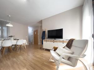 sala de estar con TV y mesa con sillas en Apartamentos Turísticos Con Alma en Plasencia