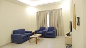 a waiting room with two blue chairs and a table at Dar Al Seef Suites in Seef