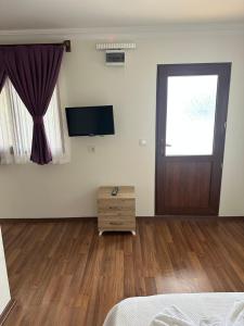 a bedroom with a bed and a door and wooden floors at yenivadi in Antalya