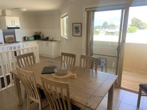 kuchnia i jadalnia z drewnianym stołem i krzesłami w obiekcie Inverloch Cabins & Apartments w mieście Inverloch