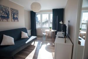 ein Wohnzimmer mit einem blauen Sofa und einem TV in der Unterkunft Apartament Monte in Sopot