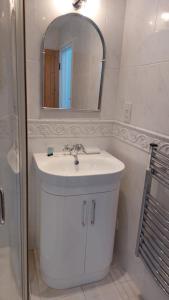 a white bathroom with a sink and a mirror at Peaceful Self-contained room near Looe in Looe