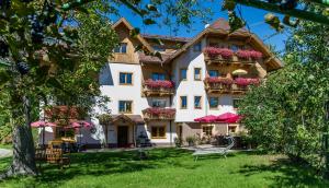 Un grand bâtiment blanc avec des fleurs sur les balcons dans l'établissement Appartements Allmaier, à Pörtschach am Wörthersee