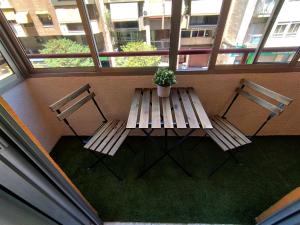 two benches and a table with a potted plant on a balcony at ROOMS in SHARED APARTMENT with HOST in Alicante