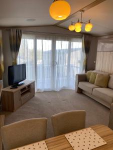 a living room with a couch and a tv at Glade 50 Bideford Bay Holiday Park in Bideford