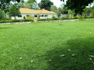un campo de césped verde con una casa en el fondo en Talpa Residences. en Tororo