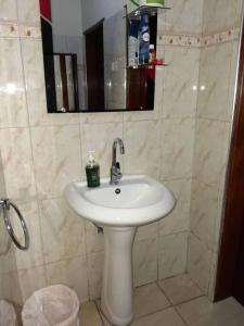 y baño con lavabo blanco y espejo. en Talpa Residences. en Tororo