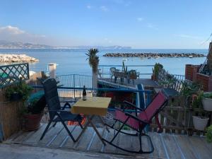 a table and chairs on a deck with a view of the water at MareVestrum - incantevole casa con accesso diretto in spiaggia in Bacoli