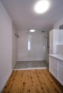 a white bathroom with a shower and a wooden floor at Großzügige Wohnung auf dem Hof Historischen Mühle in Holzhausen