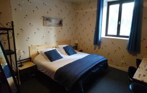 a bedroom with a bed with blue sheets and a window at Chambres d'Hôtes Le Pont in Égletons